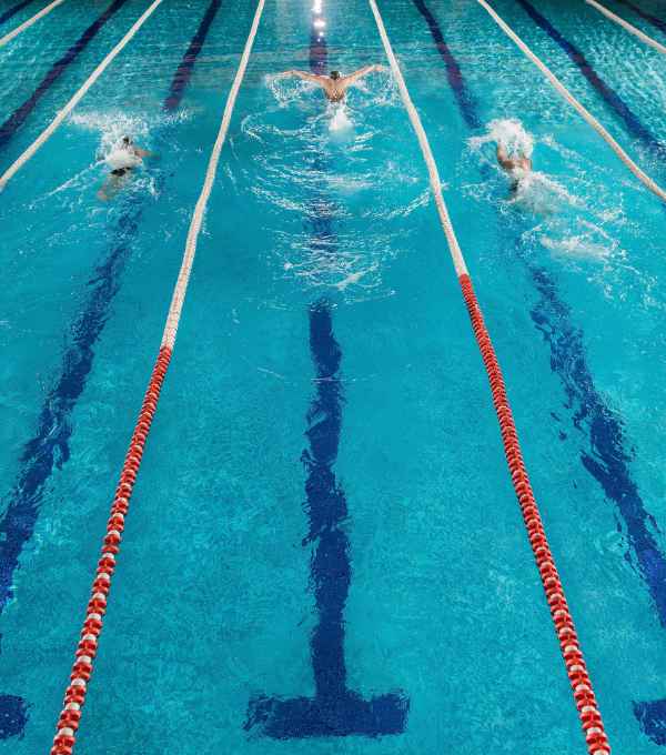 Five male swimmers doing the butterflies stroke while racing against each other in a swiming pool